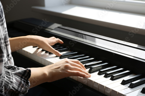 Young woman playing piano at home, closeup
