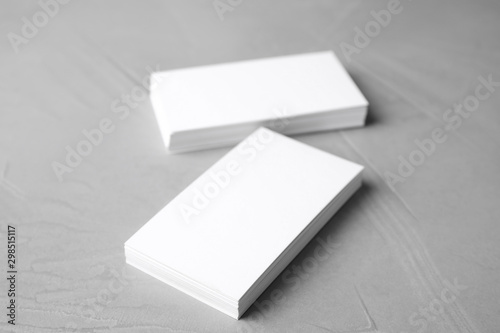 Blank business cards on light grey stone background, closeup. Mock up for design