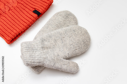 Orange knitted hat and warm winter mittens on white background