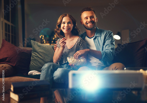 Family couple watching television projector at home on sofa.