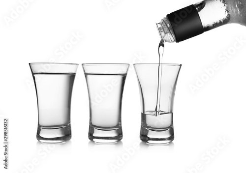 Obraz na płótnie Pouring cold vodka into shot glass on white background