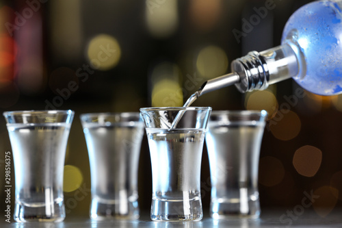 Cuadro en lienzo Pouring vodka from bottle into shot glass on bar counter