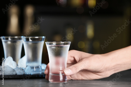 Canvas Print Woman with shot of vodka at table in bar, closeup