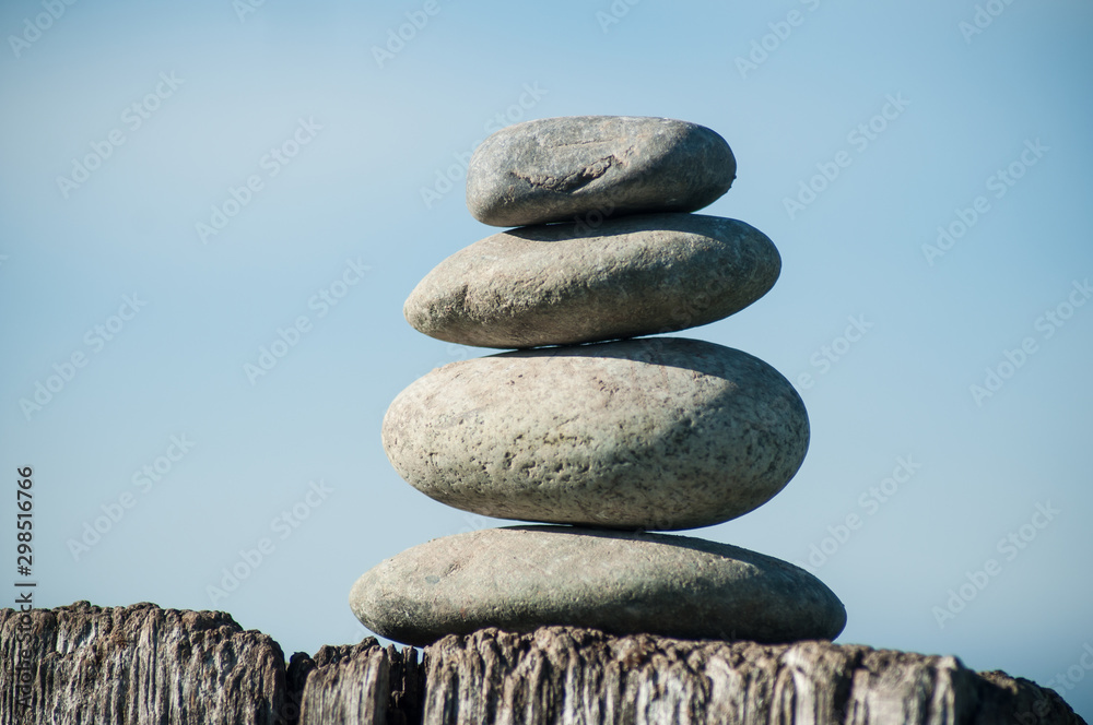 Closeup of stone balance on wooden fence on blue sky backgroundv Closeup of stone balance on wooden fence on blue sky backgroundv