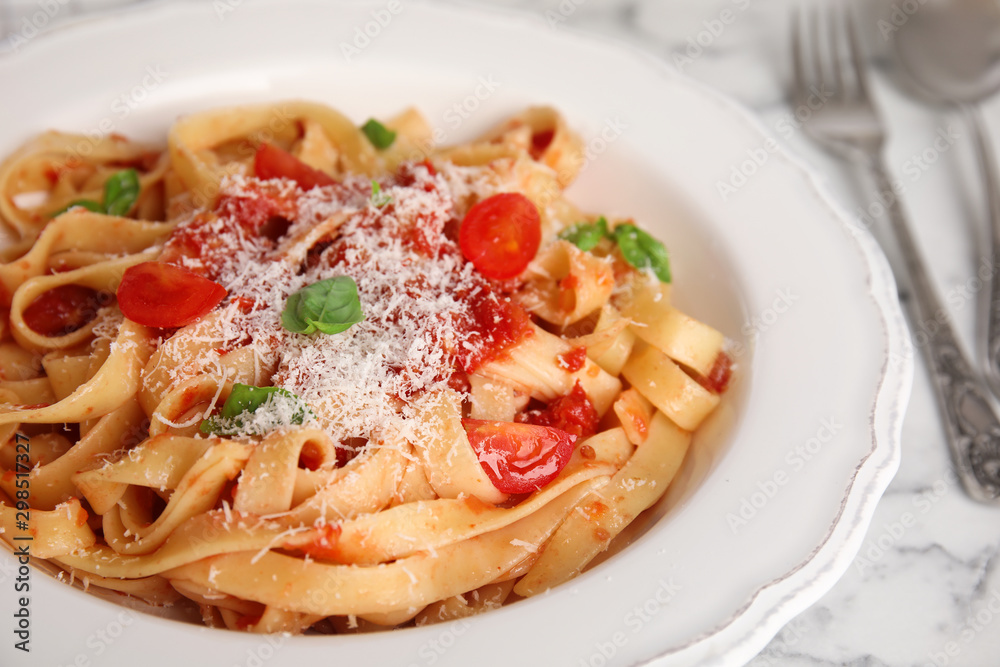 Fototapeta premium Tasty pasta with tomatoes, cheese and basil on white marble table, closeup