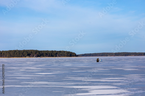 Ice skating and fishing over the frozen baltic sea in Naantali, Finland. Sunny winter day with bright blue sky.