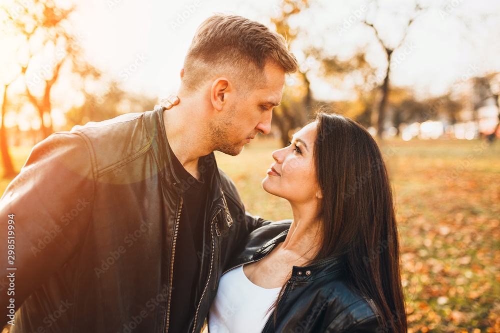 Fototapeta premium Young couple in love look each other in the eye with tenderness and passion - Caucasian man and East Asian girl