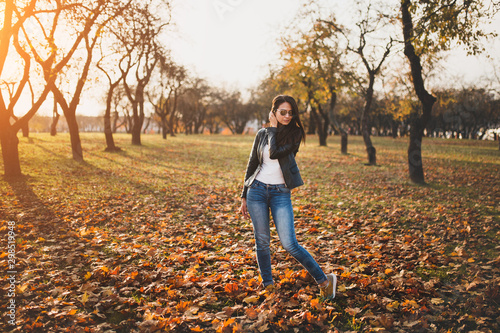 Slender long-haired slender brunette in jeans and a jacket in the autumn forest