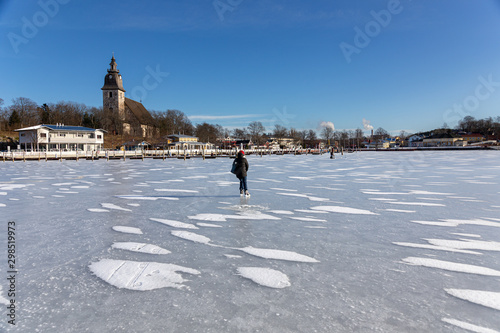 Ice skating and fishing over the frozen baltic sea in Naantali, Finland. Sunny winter day with bright blue sky.