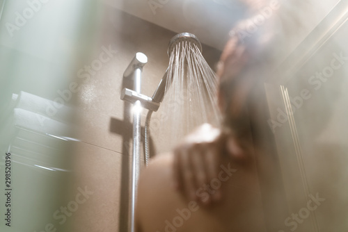 Fotografija Young diverse woman taking a shower in the bathroom and getting ready for work -
