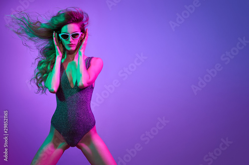 High Fashion. Party disco girl with pink neon hairstyle dance. Sensual woman in Colorful uv Light. Vibrant fashionable creative Style. Night Club music vibes, dancing. gel filter lighting, neon color