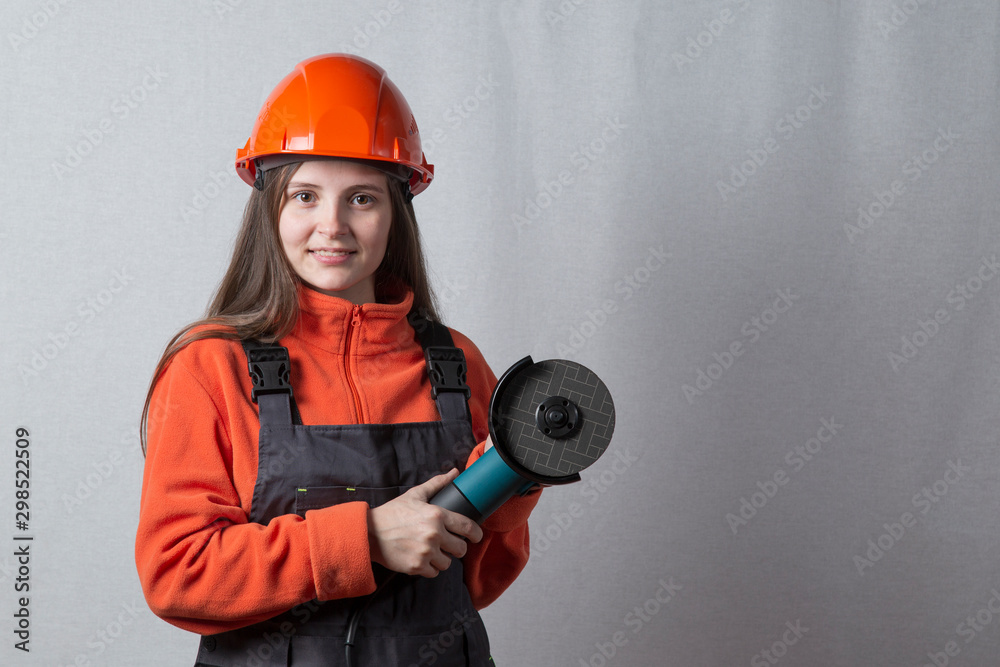 Portrait of a beautiful girl in a construction helmet and with a grinding machine. Portrait of a beautiful girl in a construction helmet and with a grinding machine.