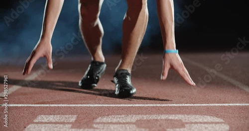 Asian athlete having an evening training, putting himself on starting position, then blasting off and sprinting, isolated on black background- sports concept 4k footage photo
