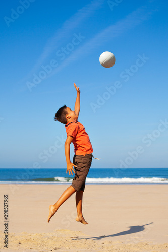 Little happy boy hit volleyball ball over sea
