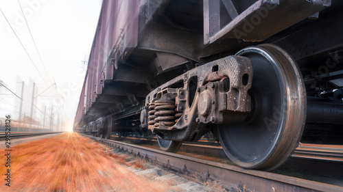 A heavy freight train travels quickly by rail. Sensation of movement by blurring the background. Fast cargo delivery by train. Side bottom view of the train