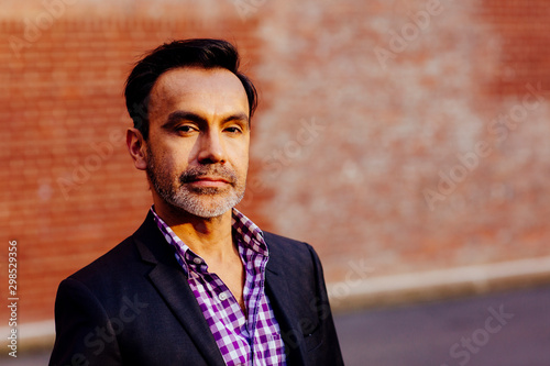 Portrait of a mature, stylish man in front of brick wall