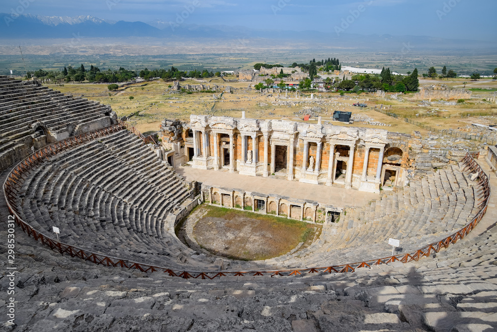 Ancient antique amphitheater in city of Hierapolis in Turkey. Steps and antique statues with columns in the amphitheater