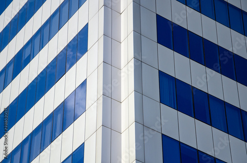 Modern architectural background of metal panels and blue glazing close up