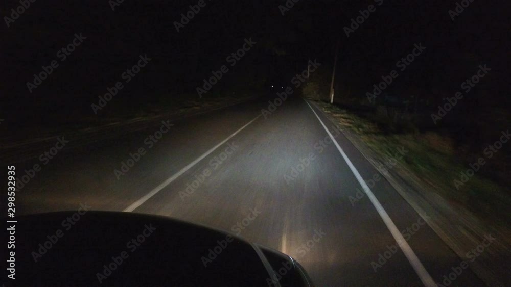 Movement of car at Night with headlights in midst of total darkness, only road with white markings and roadside signs edges of highway Movement of car at Night with headlights in midst of total darkness, only road with white markings and roadside signs edges of highway