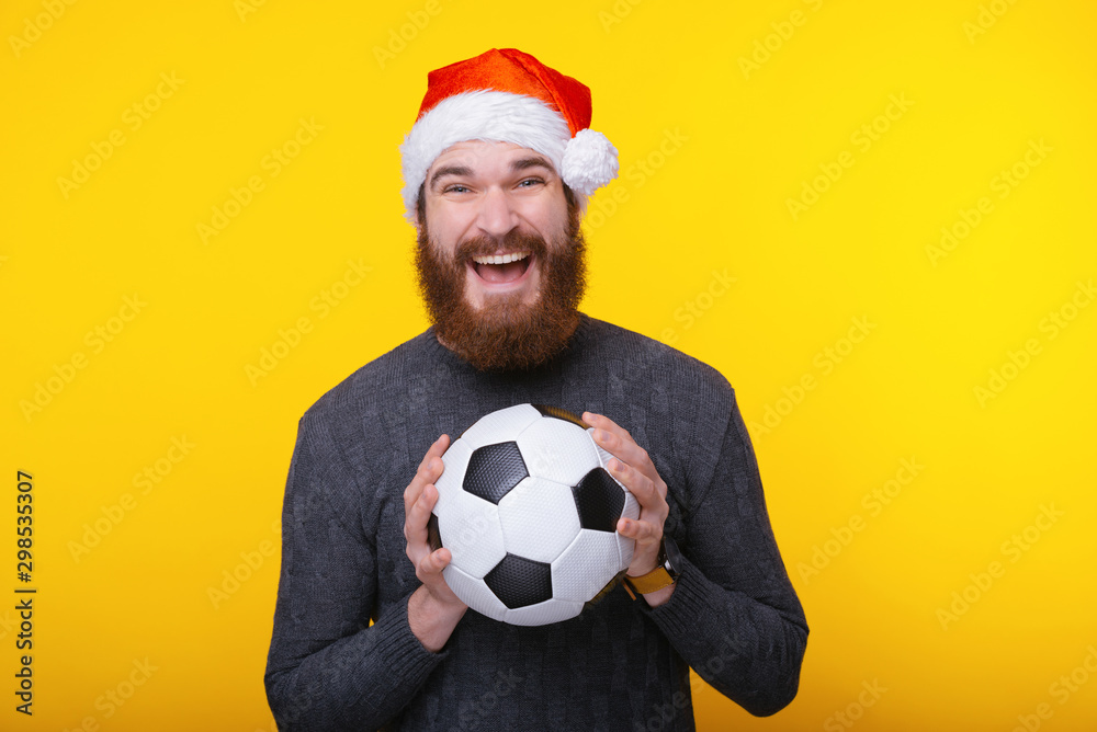Ταπετσαρία Smiling young man with santa claus hat holding soccer ball