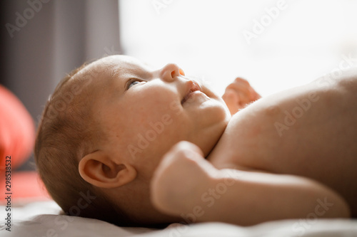 Closeup profile portrait of little baby lying in bed on her back
