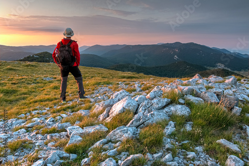 The mountaineer standing on the top of the Alancic mountin in the Velebit mountain range photographing with the phone, Croatia