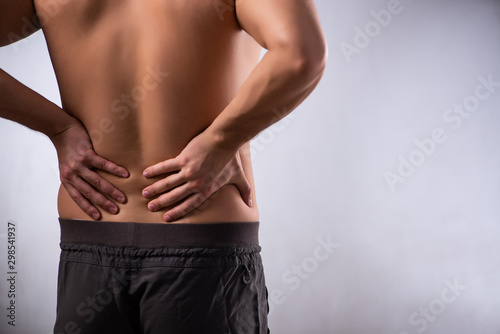 Man suffering from backbain on gray