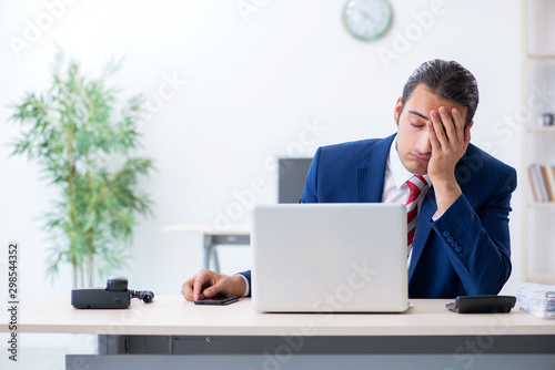 Foto Young male businessman sitting in the office