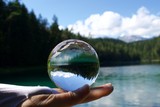 crystal ball resting on hand with reflection of Lake Eibsee
