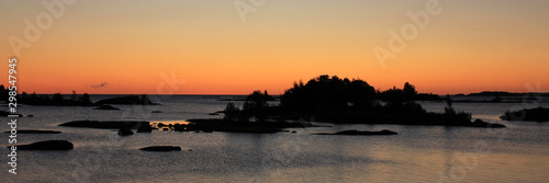 Bright orange morning sky over small islands near the shore of Lake Vanern.