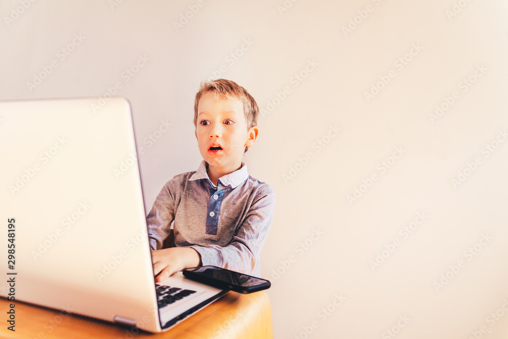 Child with very expressive face in front of a laptop with angry gesture. Child with very expressive face in front of a laptop with angry gesture.