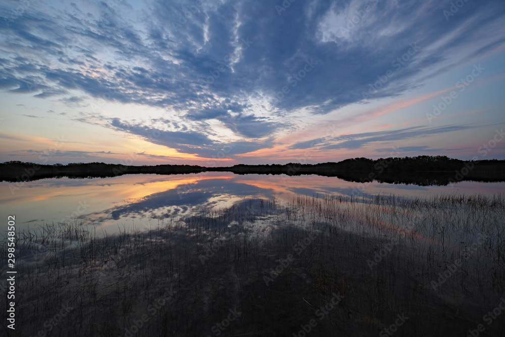 Sunrise clouds reflected on calm water of Nine Mile Pond in Everglades National Park, Florida.