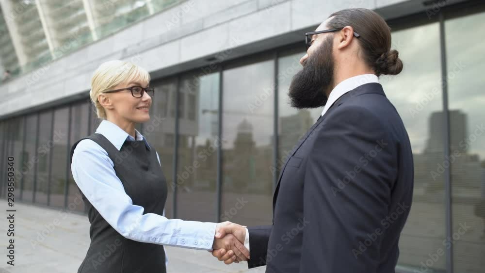 Male and female colleagues shaking hands in street, business cooperation meeting