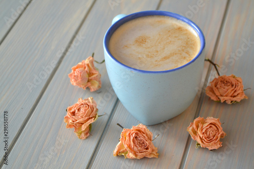 Coffee cup and dry rose flowers in cremy color on blue vintage table, provence style photo