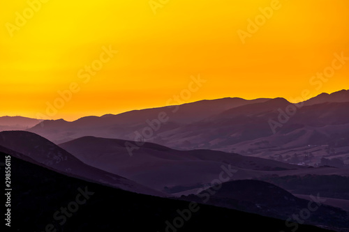 Yellow Sunrise over Silhouetted Mountains