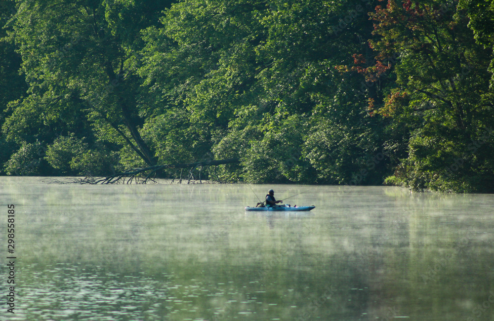 Lone kayaker fishing on the early morning lake Lone kayaker fishing on the early morning lake
