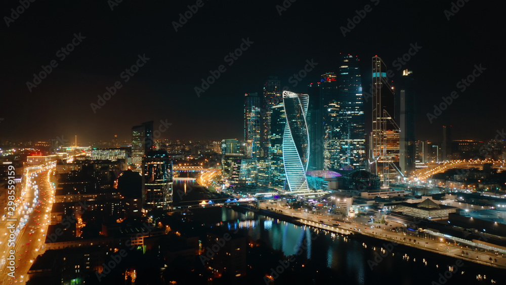 Picturesque aerial panorama of Moscow City Business Center on the night with bright glittering lights of buildings, streets and traffic. Camera slowly moves away showing amazing cityscape.