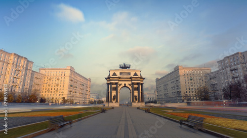 Motion of a busy Moscow avenue on the evening. Camera moving along the boulevard and passing the Triumphal Gate with a lot of traffic on both sides of the walkway and beautiful cloudscape.