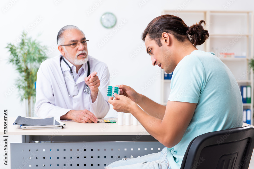 Young man visiting old male doctor Young man visiting old male doctor