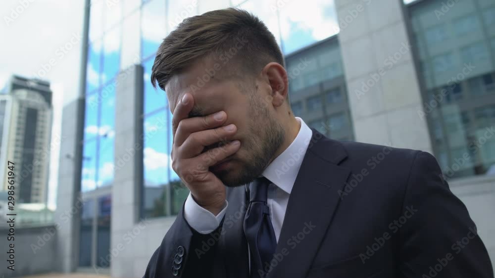 Desperate man in business suit covering face with hands, losing job, bankruptcy Desperate man in business suit covering face with hands, losing job, bankruptcy