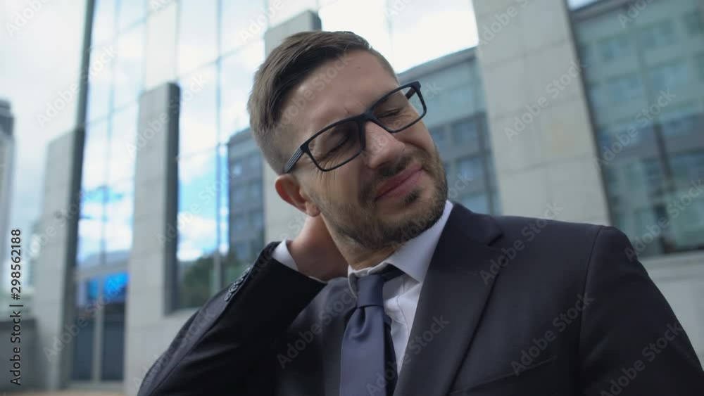 Male entrepreneur in glasses suffering neck pain, muscle spasm, inflammation Male entrepreneur in glasses suffering neck pain, muscle spasm, inflammation