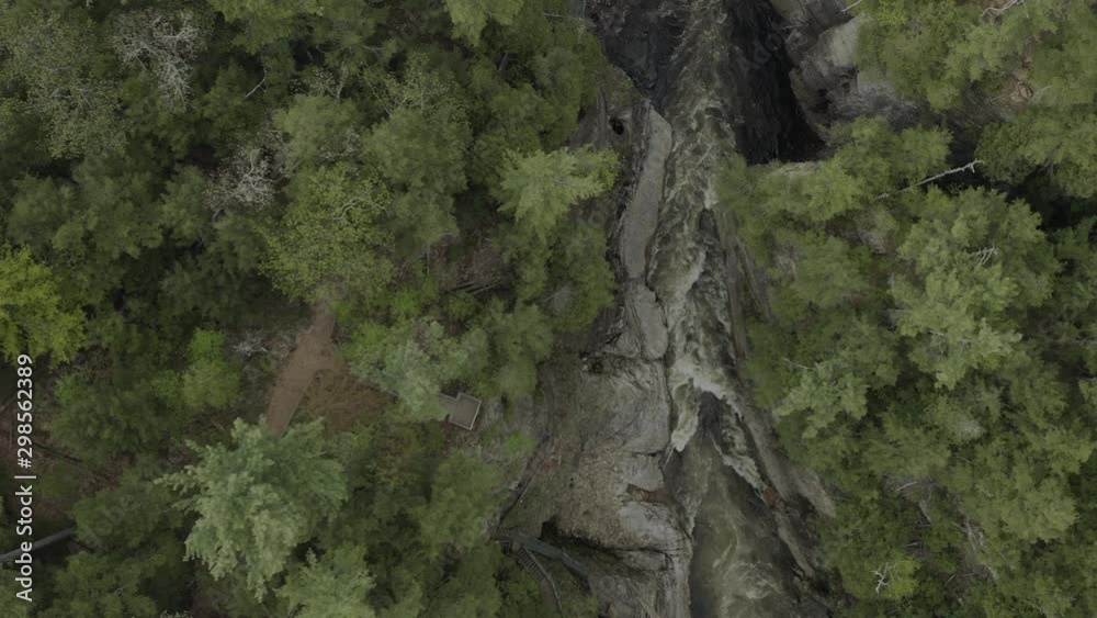 Drone shot flying to the right facing the camera down, flying over a forest and canyon with water going through it. Drone shot flying to the right facing the camera down, flying over a forest and canyon with water going through it.