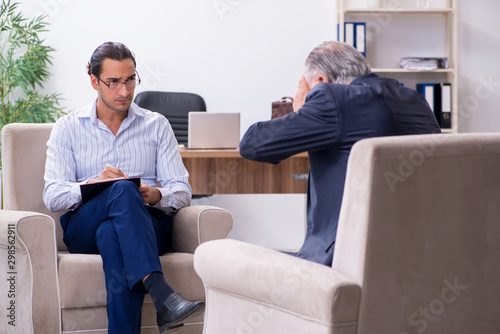 Old man visiting young male doctor psychologist