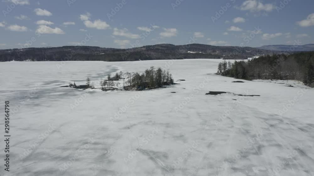 Drone shot flying forwards over a frozen lake with trees on the shores. Drone shot flying forwards over a frozen lake with trees on the shores.