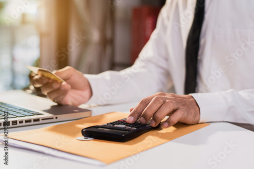 Businessman using calculator with credit card for shopping internet online in office.