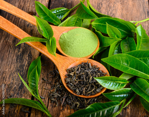 heap of dried green tea leaf and powder on wooden background