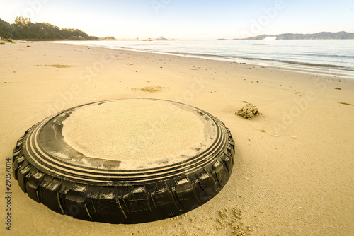 old car rubber tire burried on the sandy beach