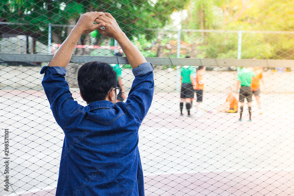 Obraz premium A man looking and cheering futsal competitions at school in sunset time.