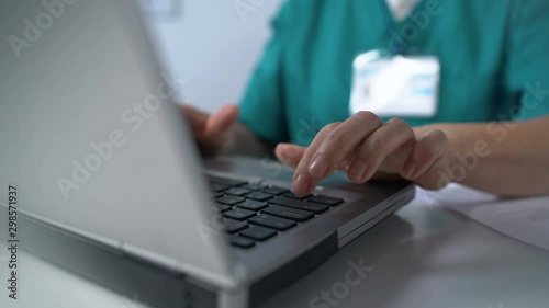 Nurse typing on laptop pc, completing medical documentation online, consultation