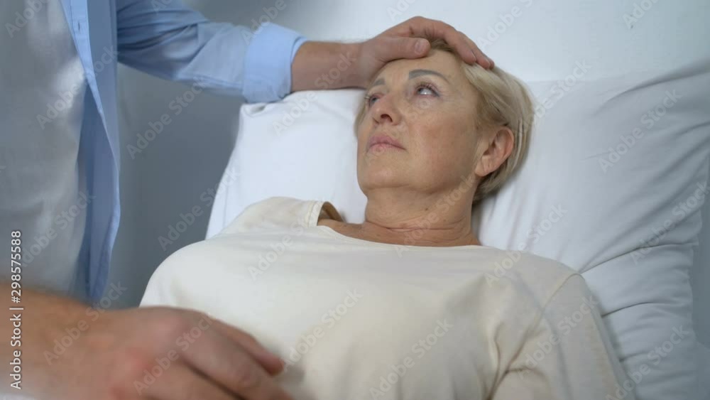Loving son supporting and comforting terminally-ill mother in her hospital ward Loving son supporting and comforting terminally-ill mother in her hospital ward